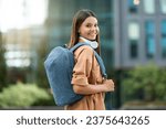Small photo of Young woman student with backpack walking through campus. Joyful pretty lady posing at university park, exuding positivity and a thirst for knowledge amidst an atmosphere of academic pursuit