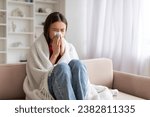 Young Sick Asian Woman Blowing Nose In Paper Tissue While Sitting On Couch At Home Covered In Blanket, Portrait Of Ill Korean Female Suffering Runny Nose, Feeling Unwell, Having Seasonal Flu
