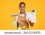 Small photo of Spring cleanup. Professional African American cleaner with squeegee scrubber and detergent, promoting effective disinfection and hygiene, against yellow studio background, enjoying house chores