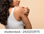 Small photo of Unhappy young woman scratching her irritated skin on arm, annoyed indian female wearing white top suffering eczema or dermatitis, having itching rash on body, standing on beige studio background