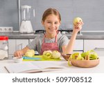 cheerful little girl with peeled apple in hand and on the table with recipe book