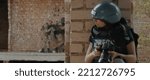 Small photo of Caucasian female war journalist wearing protective helmet and bulletproof vest gear taking photos during military operation