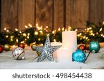 Small photo of Christmas background with white candles, holiday ornaments, tin star and string of lights with green garland border in snow; red, teal blue, silver and gold rustic Christmas background