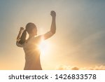 Strong woman, Winning, success , and life goals concept. Young woman with arms flexed facing the sunset. 