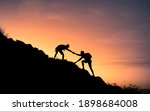 Small photo of Two male hikers helping each other climb up a mountain. Teamwork and perseverance.