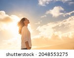 Attractive young woman looking up to the beautiful sky with feelings of hope and happiness. 