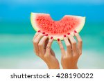 Hand holding watermelon on the beach. 