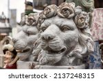 Small photo of A pair of antique decorative lion head plant pots, with roses forming the mane. Other antiques and bric-a-brac can be seen in the background of a market stall.