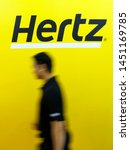Small photo of PENANG, MALAYSIA - JULY 05, 2019 : Man walk across the Hertz logo on a wall at customer service center. Hertz is an American car rental company with international locations in 145 countries worldwide.