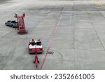 Small photo of Airplane tow tractor at the airport apron near the terminal. Aircraft Towing Tractor. A towing tractor belonging in air port is being operated by officer. Aerodrome tow tractor is driving at airport