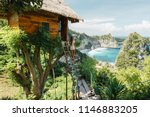 Young girl on steps of traditional house on tree, look at Atun beach, Nusa Penida island. Popular travel destination on Bali holidays. Indonesian background.  travel lifestyle concept