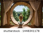 Young girl doing yoga outdoor. Young woman practicing yoga in bamboo house, nature on background.Female happiness.Caucasian woman practicing yoga on vacation on Bali island