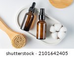 Natural bristles exfoliating brush for dry face or body massage on white background. two bottles with skin care products. Detoxing skin ritual. mockup