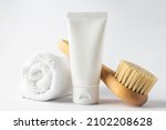 Small photo of SPA cosmetics, woman body and skincare products on white background. Natural bristle dry massage brush and body or face cream in white plastic tube