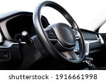 Black luxury modern car Interior. Steering wheel, shift lever and dashboard. Detail of modern car interior. Automatic gear stick. Part of leather seats with stitching in expensive car