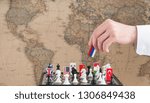 Small photo of Politician's hand moves a chess piece with a flag. Conceptual photo of a political game. retaliatory move of Russia
