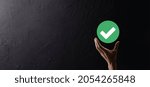 Small photo of Hand holds green icon Check mark,Check Mark Sign, Tick Icon,right sign,circle green checkmark button,Done.On dark background.Banner.Copy space.Place for text