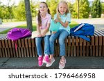 Small photo of Two cute pupils girls having fun after lessons in the schoolyard in sunny day. Children playing and laughing. Schooldays with friends. Concept back to school