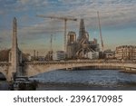 Small photo of Paris, France - 11 30 2023: Notre Dame de Paris. Panoramic view of the renovation site with scaffolding, the new steeple, Sully Bridge and the moon from Austerlitz Bridge