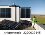 Woman on the rooftop of her house with a solar power plant installed on it. Happy owner of energy-independent household