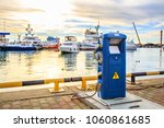 Charging station for boats, electrical outlets to charge ships in harbor. Shore in marina jetty. Electrical power sockets bollard point on pier near sea coast. Luxury yachts docked in port at sunset.