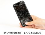 Modern black smartphone with highly broken screen in women hand on white background