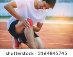 Small photo of Runner man with sports running knee injury at racetrack. Hands holding knee with painful (ankle knee twist).