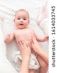 Small photo of Baby massage. Female therapist gently massaging newborn baby boy. Mother applying body lotion to her infant baby boy. Newborn massage top view background.