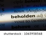 Small photo of beholden word in a dictionary. beholden concept.
