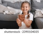 Small photo of Little crafty girl eats sweets at home. Kid eating chocolate and have fun. Chaos at home