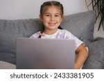 Small photo of Portrait of beautiful little girl using smart devise. Five year old girl open and use laptop