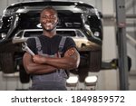 portrait of positive afro american auto mechanic in uniform posing after work, he is keen on repairing cars, automobiles.