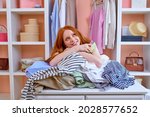 young redhead attractive caucasian woman happy positive smile hold credit card buy purchase clothes shopper sit behind table with outfits at home in cozy bright room, shopaholic. consumerism concept