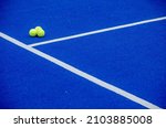 Small photo of Three paddle tennis balls on a blue synthetic grass paddle tennis court surface. Sporty life concept.