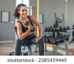 Small photo of Beautiful athletic muscular woman pumps up the muscles by one arm lifts dumbbell exercise in fitness. Young healthy woman in sportswear doing exercise in fitness.