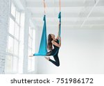 Fit pretty young woman doing fly yoga stretching exercises  in fitness training white gym loft classroom. Sport and healthy lifestyle concept. Copy space, empty space for text.