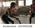 Strong woman exercising with battle ropes at the gym with male trainer. Athlete doing battle rope workout at gym with instructor.