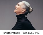 Side view of senior woman laughing on gray background. Profile view of mature woman in black casuals looking happy