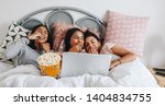 Small photo of Girls having a sleepover enjoying a movie on laptop with popcorns. Three young girls having fun watching movie on laptop eating popcorns in a tub during a sleepover.