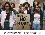 Group of activists with banners protesting over pollution and global warming. Male and female rebellions doing a silent protest to save planet earth. Woman holding a banner of 'There is no Planet B'.