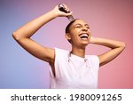 Small photo of Smiling woman shaving her head. Bold and liberated female cutting her hair with an electric trimmer against multicolored background.