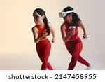 Small photo of Fitness in the metaverse. Sporty young woman playing a virtual reality fitness game as a 3D avatar. Athletic young woman running with virtual reality goggles and controllers.