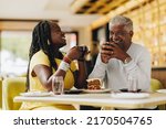 Small photo of Happy senior couple laughing cheerfully while having coffee together in a cafe. Carefree senior couple having a good time in a restaurant. Mature couple enjoying their retirement together.