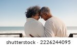 Small photo of Sharing a romantic moment at the beach. Rearview of a happy senior couple touching their foreheads together on a seaside bridge. Retired elderly couple spending some quality time together.