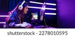 Small photo of Happy girl live streaming a video game, sitting in front of a multi monitor with a microphone for commentary and a headset for communication. Female engaging with fellow gamers on an online platform.