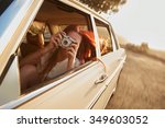 Shot of  young woman taking photos while sitting in a car. Female capturing a perfect road trip moment.
