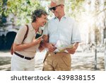Retired couple walking around the town with a map. Smiling mature man and woman roaming around the city.