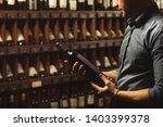 Small photo of Close up portrait of sommelier holding wine bottle on wine cellar background.