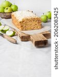Small photo of Apple and coconut oaf cake on wooden cutting board and apples in a vase. Copy space
