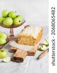 Small photo of Apple and coconut oaf cake on wooden cutting board and apples in a vase